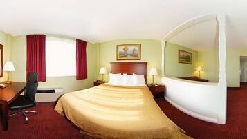 A hotel room with a bed, desk, chair, and two bedside tables with lamps.