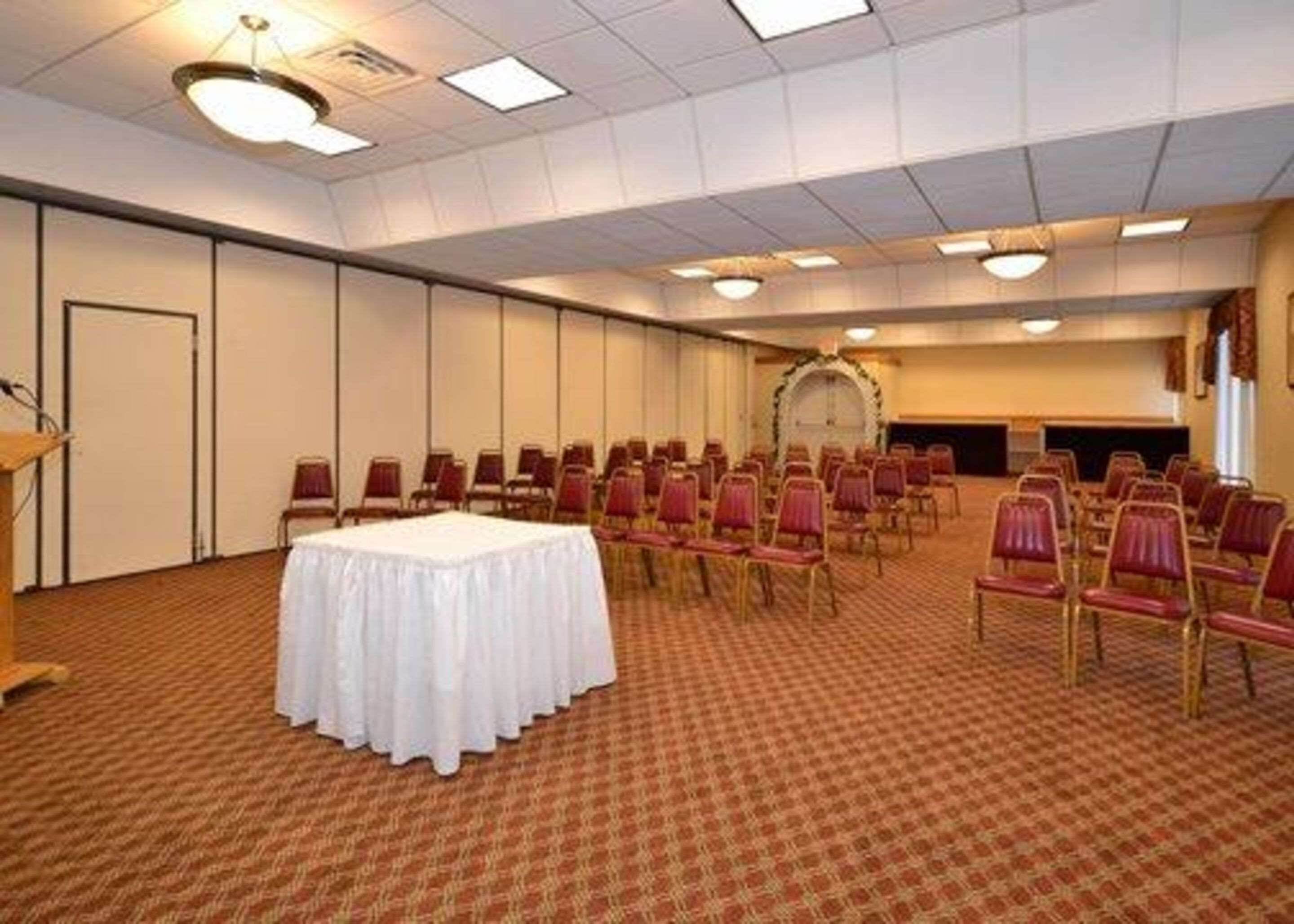 A conference room with a round table, rows of chairs, and a podium.