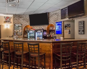 Eine Bar mit Backsteinwand, Flachbildfernseher und einer Getränkekarte.