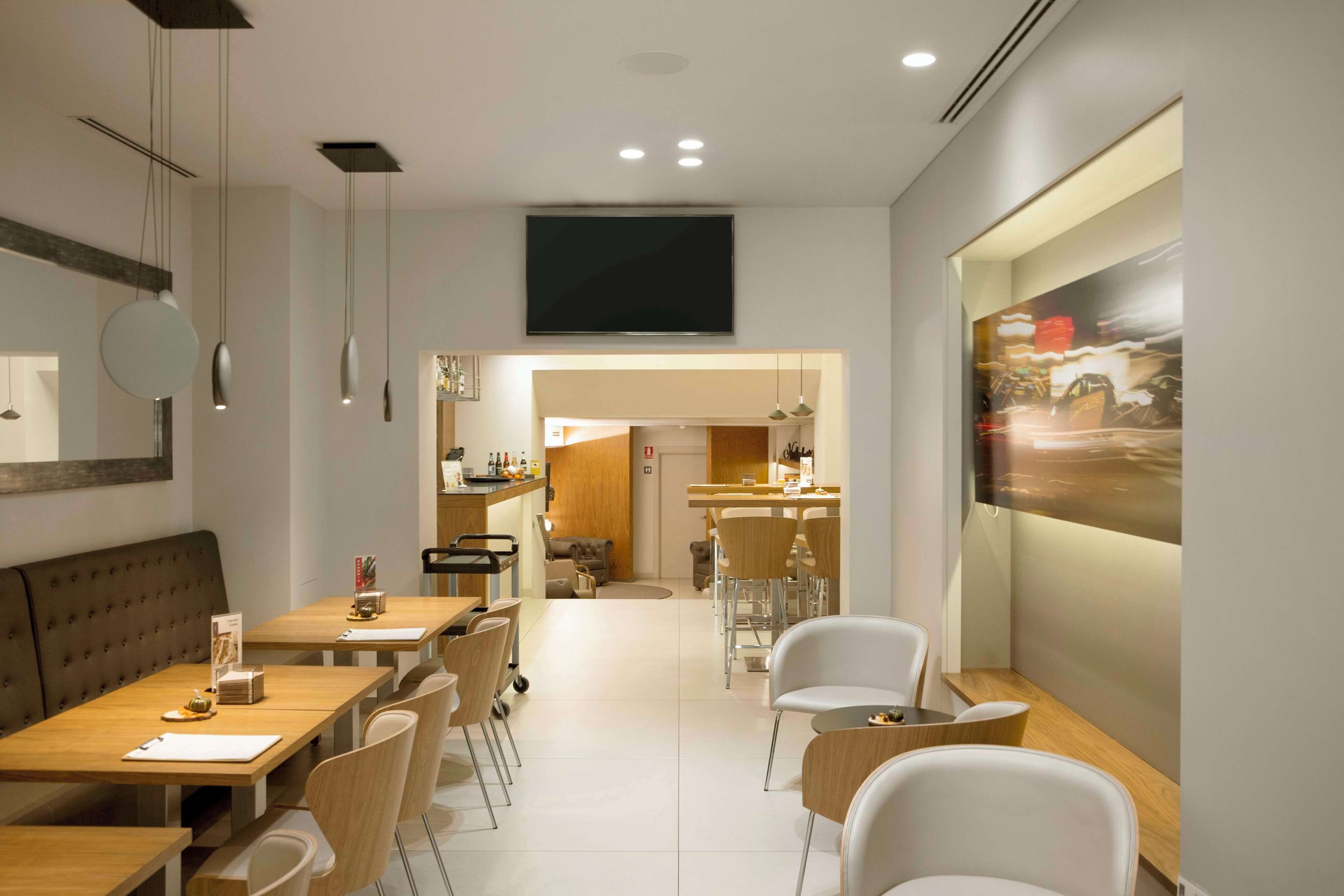 Un comedor moderno con una mesa larga, varias sillas y un televisor montado en la pared.