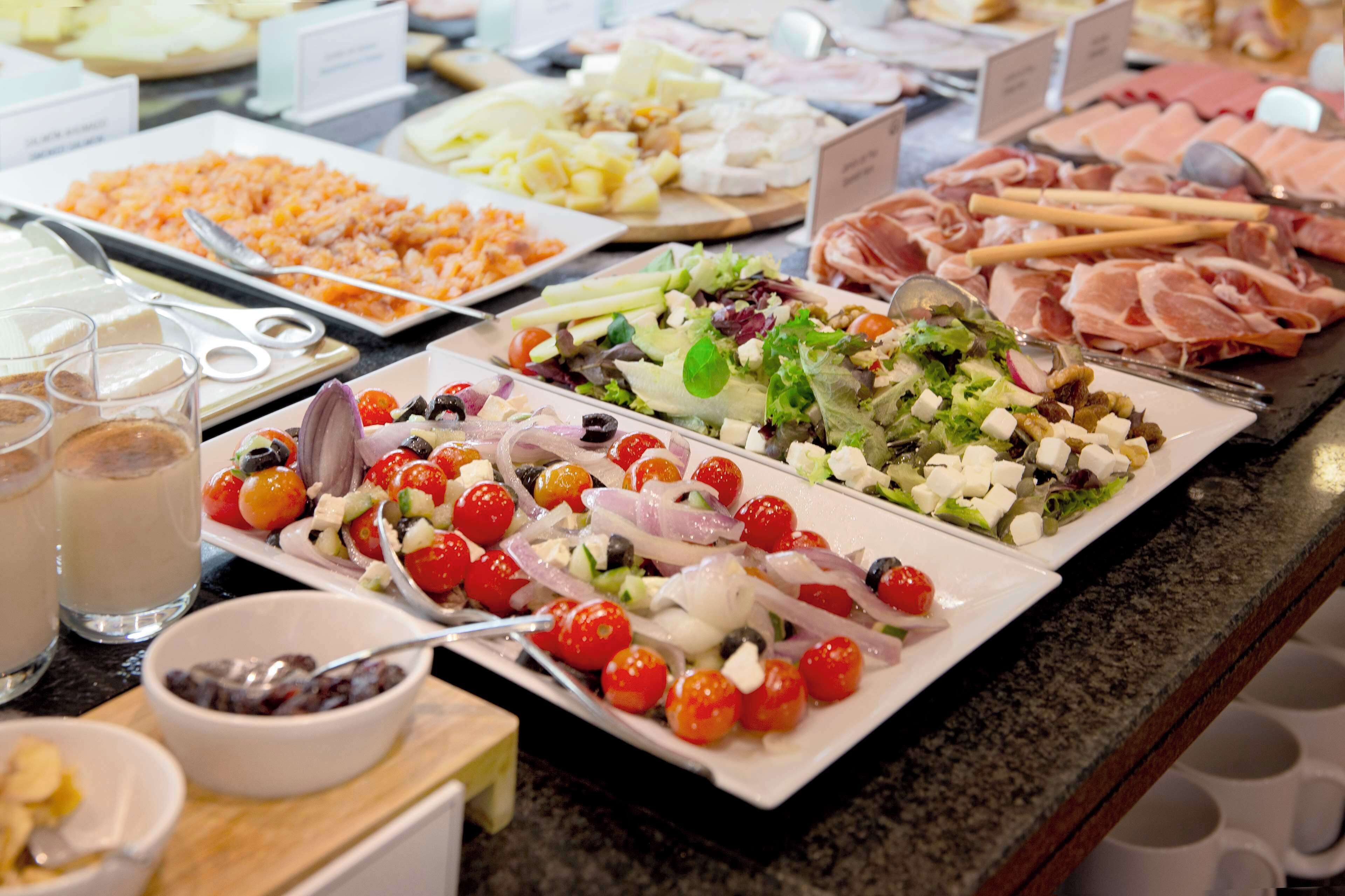 A buffet with various food items including salads, meats, and cheeses.