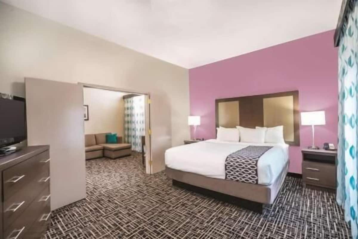 Una habitación de hotel con una cama, televisión, escritorio y una silla.