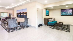 En modern entréhall med sittgrupper, en stor målning som föreställer en stadsbild och en dörr som leder till ett annat rum.