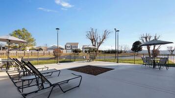 An outdoor patio area with sun loungers, tables, and umbrellas.