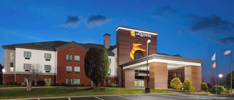 Un hotel con un letrero destacado de 'La Quinta', un estacionamiento y un césped bien cuidado.