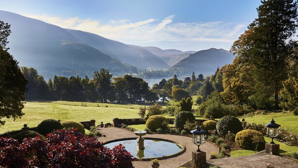 A landscaped garden with a circular pond, neatly trimmed hedges, and a distant view of mountains. - Macdonald Leeming House (Penrith)