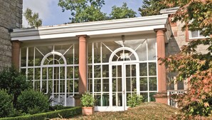 A building with large arched windows, a stone facade, and a well-maintained garden. - Macdonald Leeming House (Penrith)