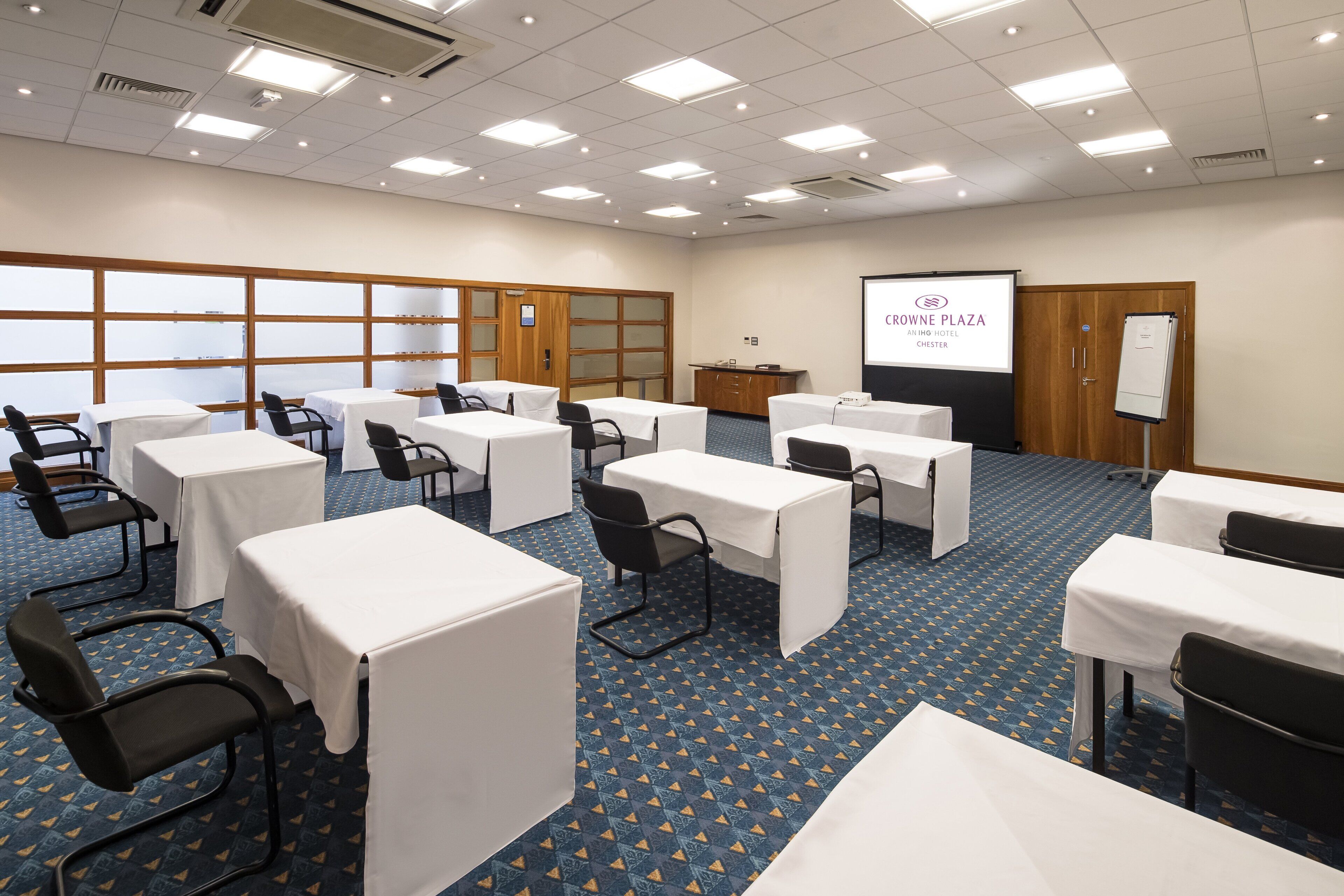 Una sala conferenze con tavoli e sedie, uno schermo per proiettore e uno schermo per presentazioni.