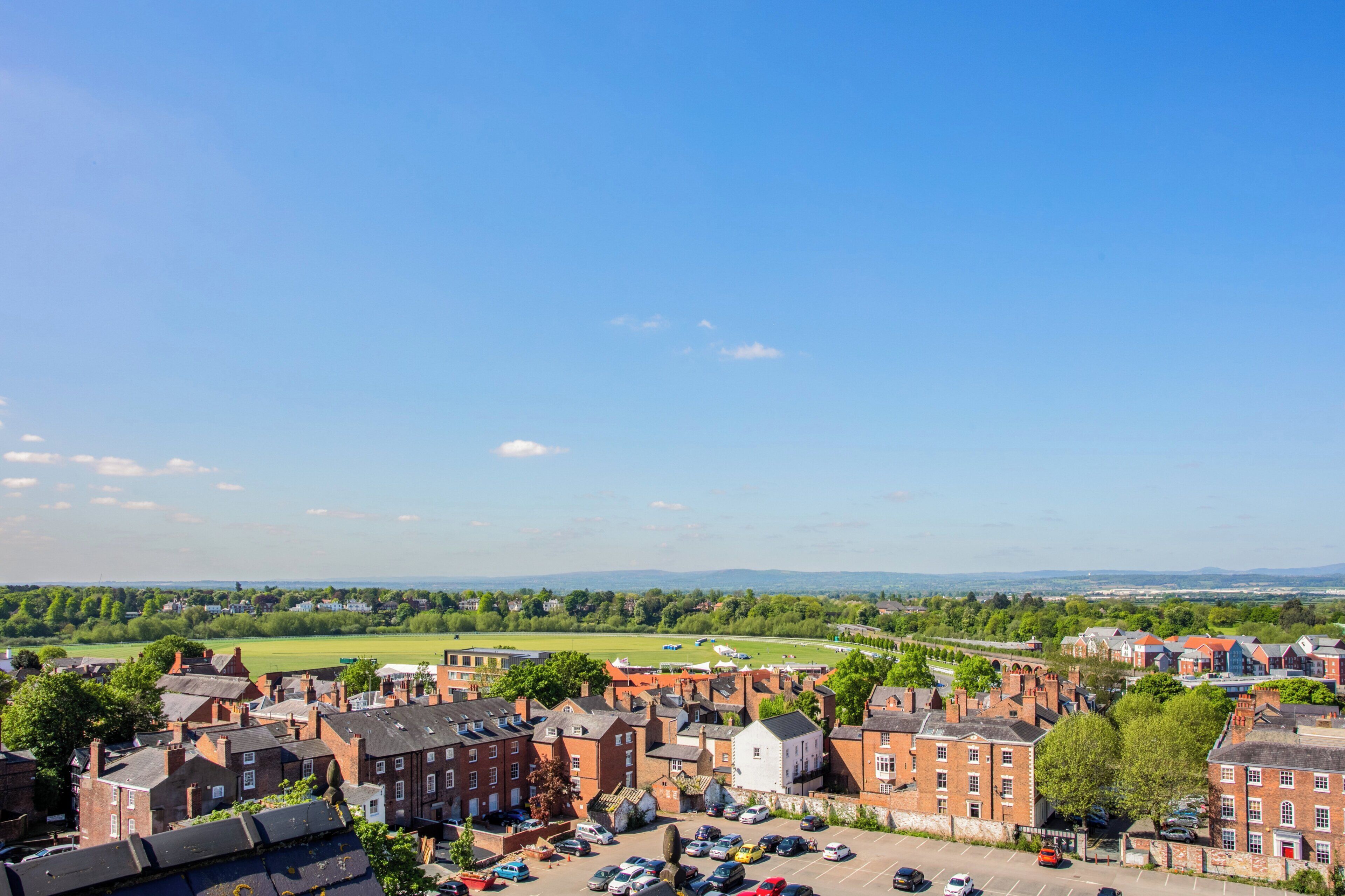 A town with red brick buildings, a parking lot, and a clear blue sky.