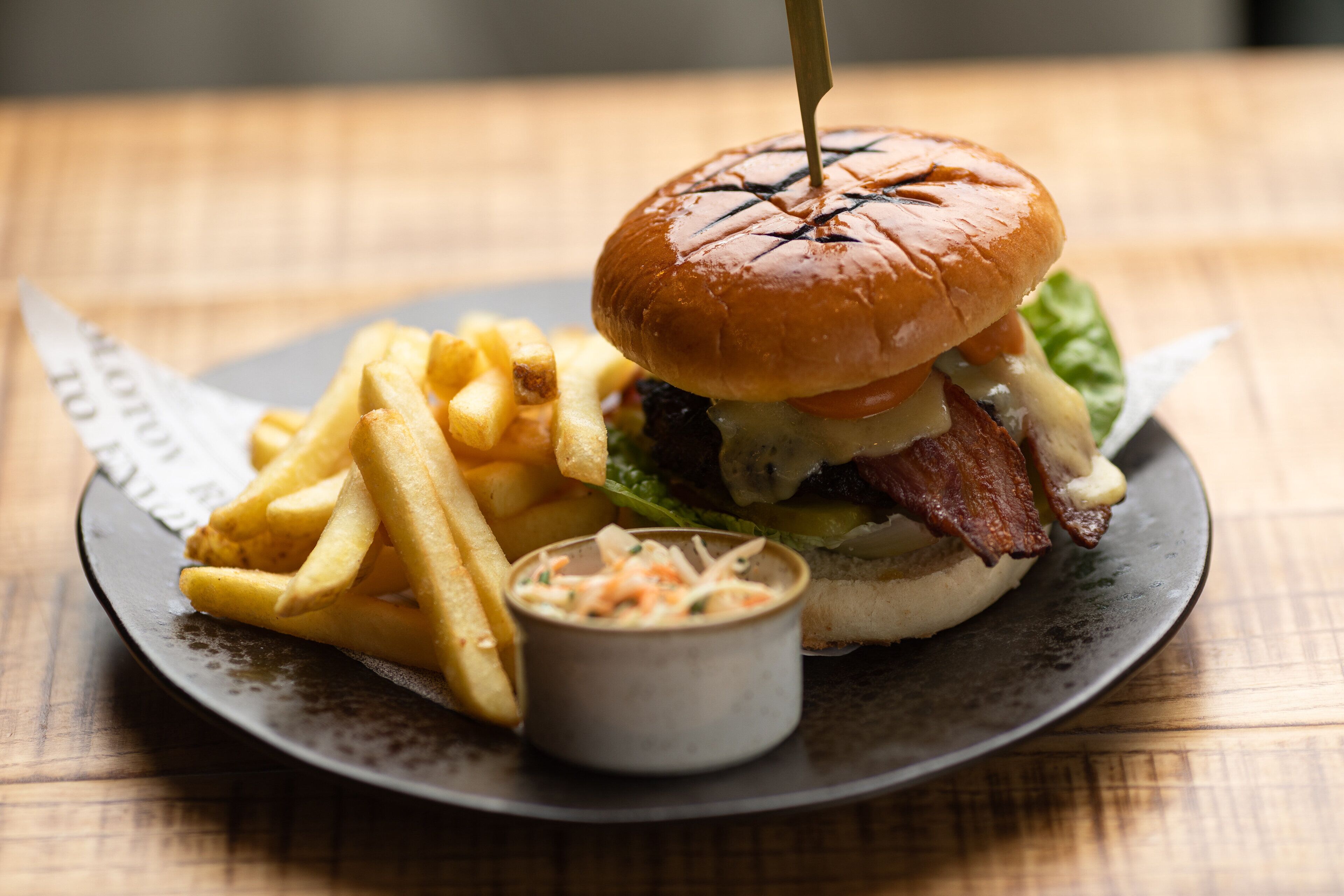 Een bord met een hamburger, friet en een klein bakje saus.