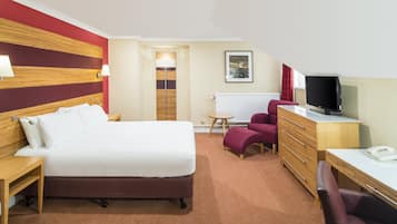 Una camera d'albergo con un letto, una scrivania, una televisione, una sedia e una lampada.