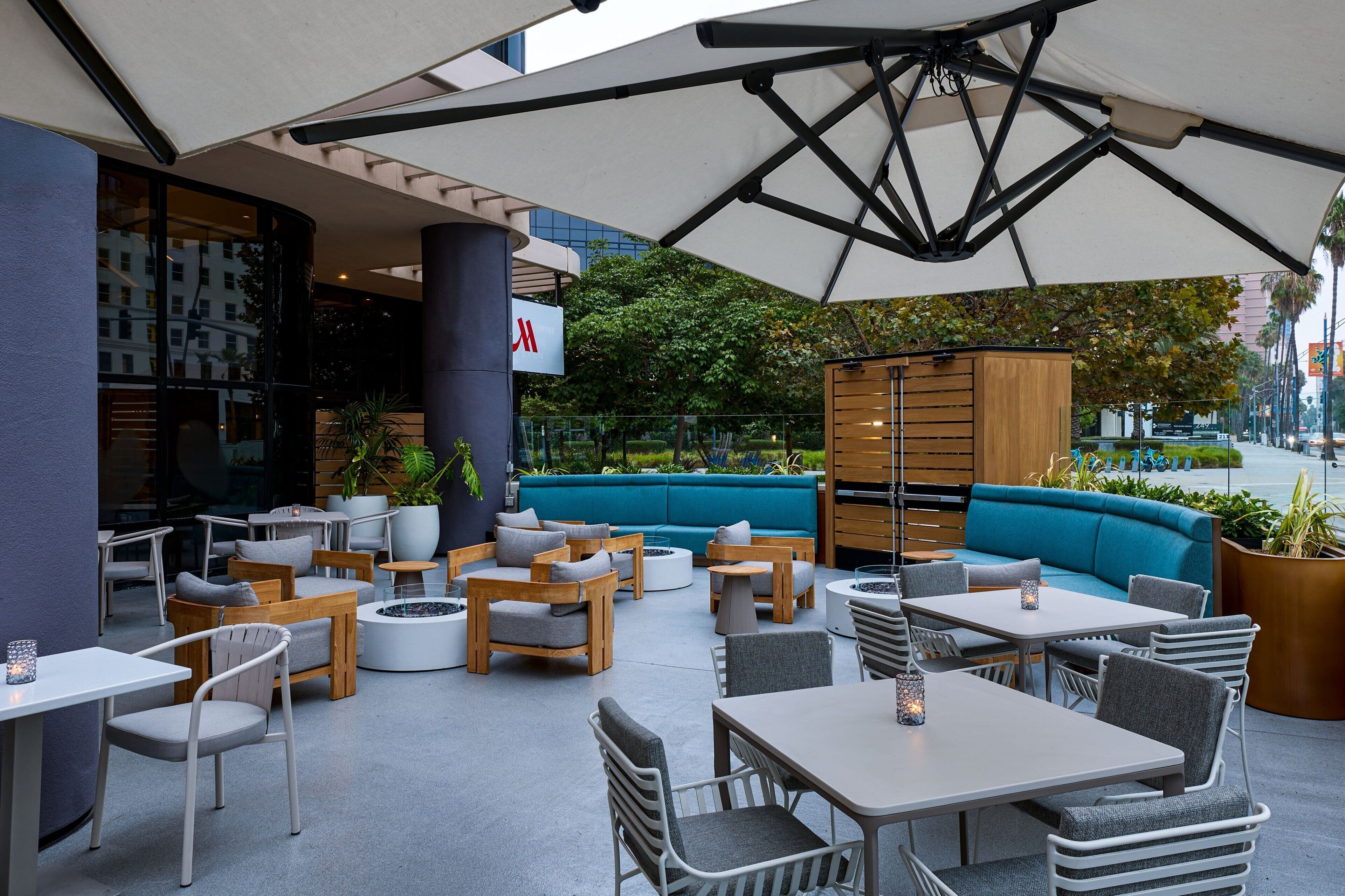 An outdoor seating area with tables and chairs, a blue sofa, and a wooden cabinet.
