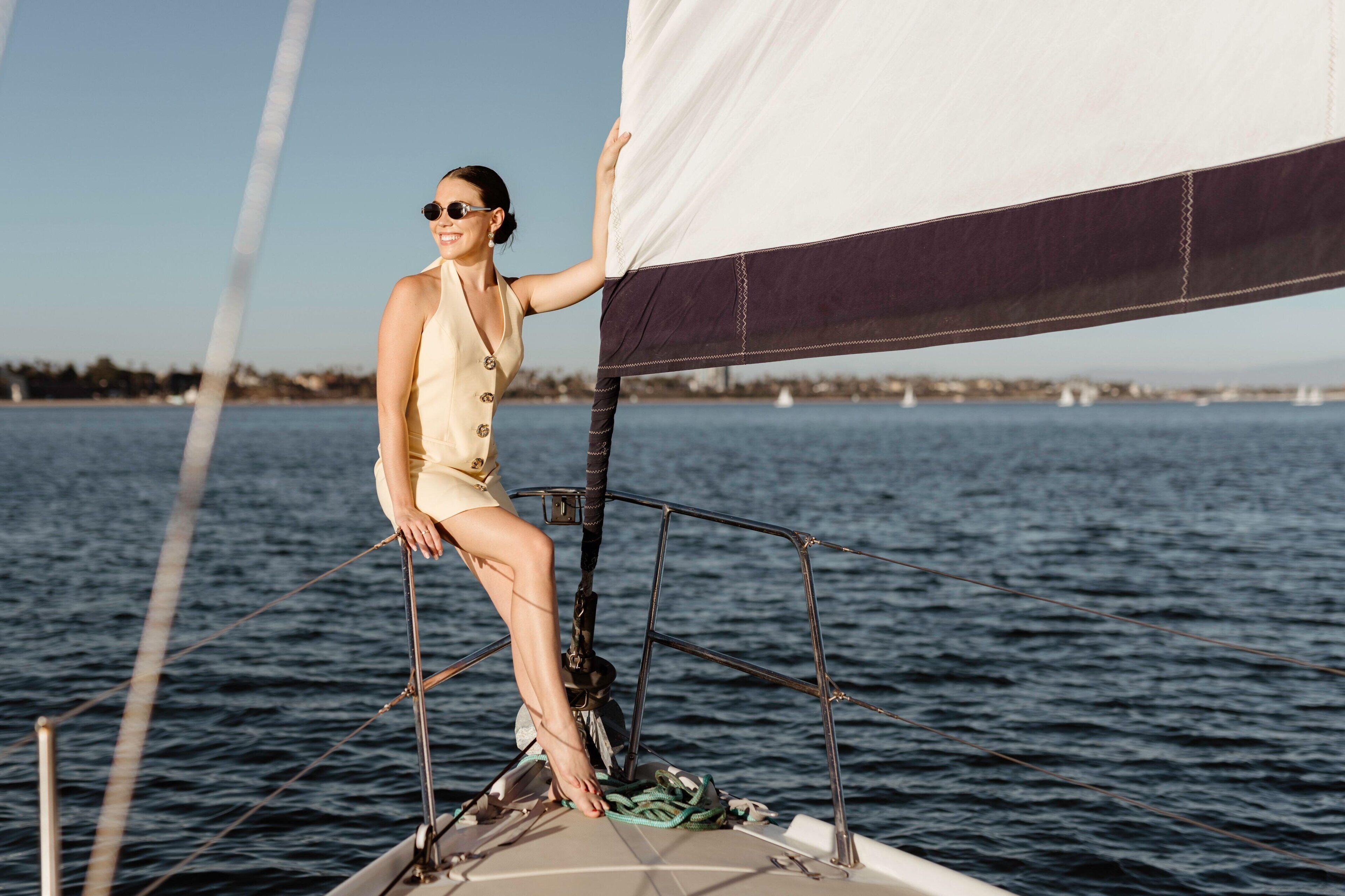 A person on a sailboat with a clear view of the water and distant shoreline.