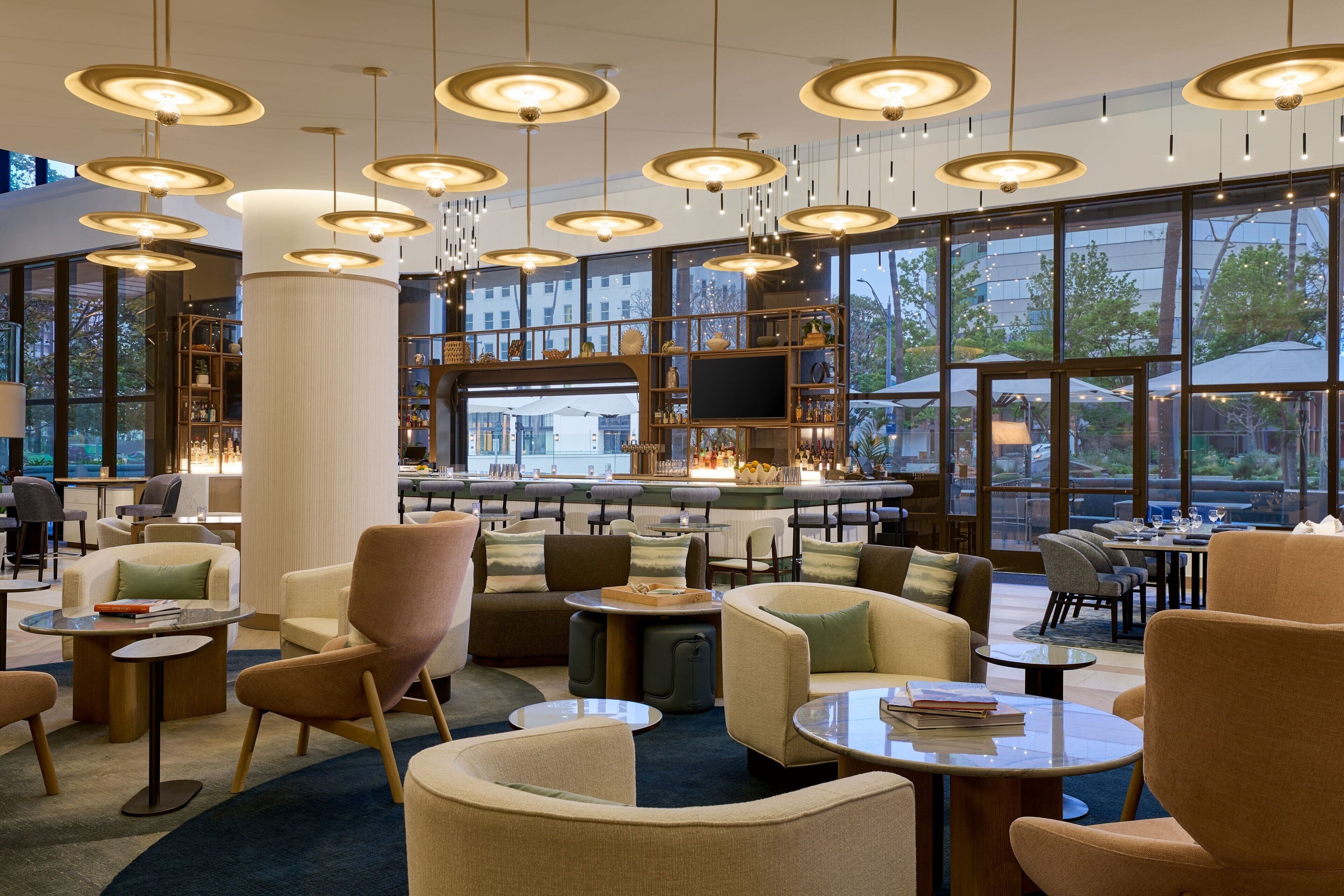 Et moderne loungeområde med flere siddepladser, en bar og store vinduer med udsigt over naturen.
