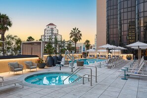 A rooftop pool area with lounge chairs, umbrellas, and a pool.