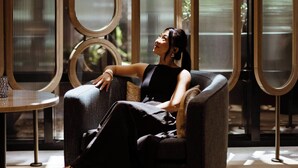 A woman seated on a modern sofa in a room with large windows and a decorative metal partition. - Marriott Long Beach Downtown (Long Beach)