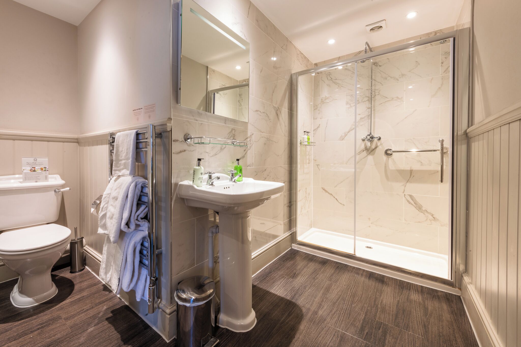 A modern bathroom with a toilet, sink, and glass-enclosed shower.