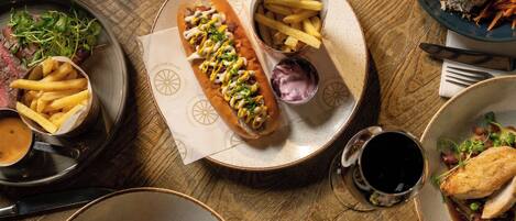 A variety of dishes on a wooden table, including a sandwich, fries, and a salad.