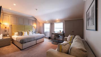 A modern hotel room with a large bed, a desk, and a sofa.