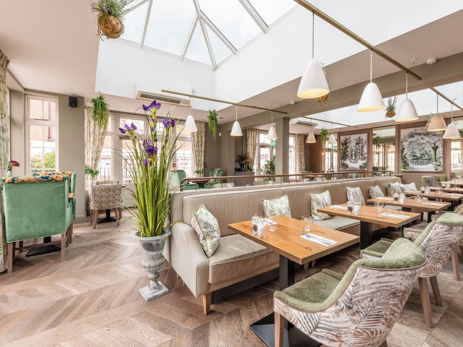 A spacious restaurant with high ceilings, large windows, and a variety of seating options including booths and tables.