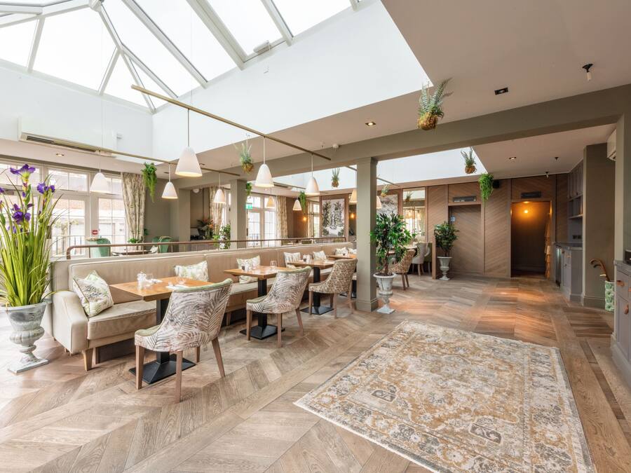 A spacious indoor area with high ceilings, large windows, and a variety of seating arrangements including tables and chairs.
