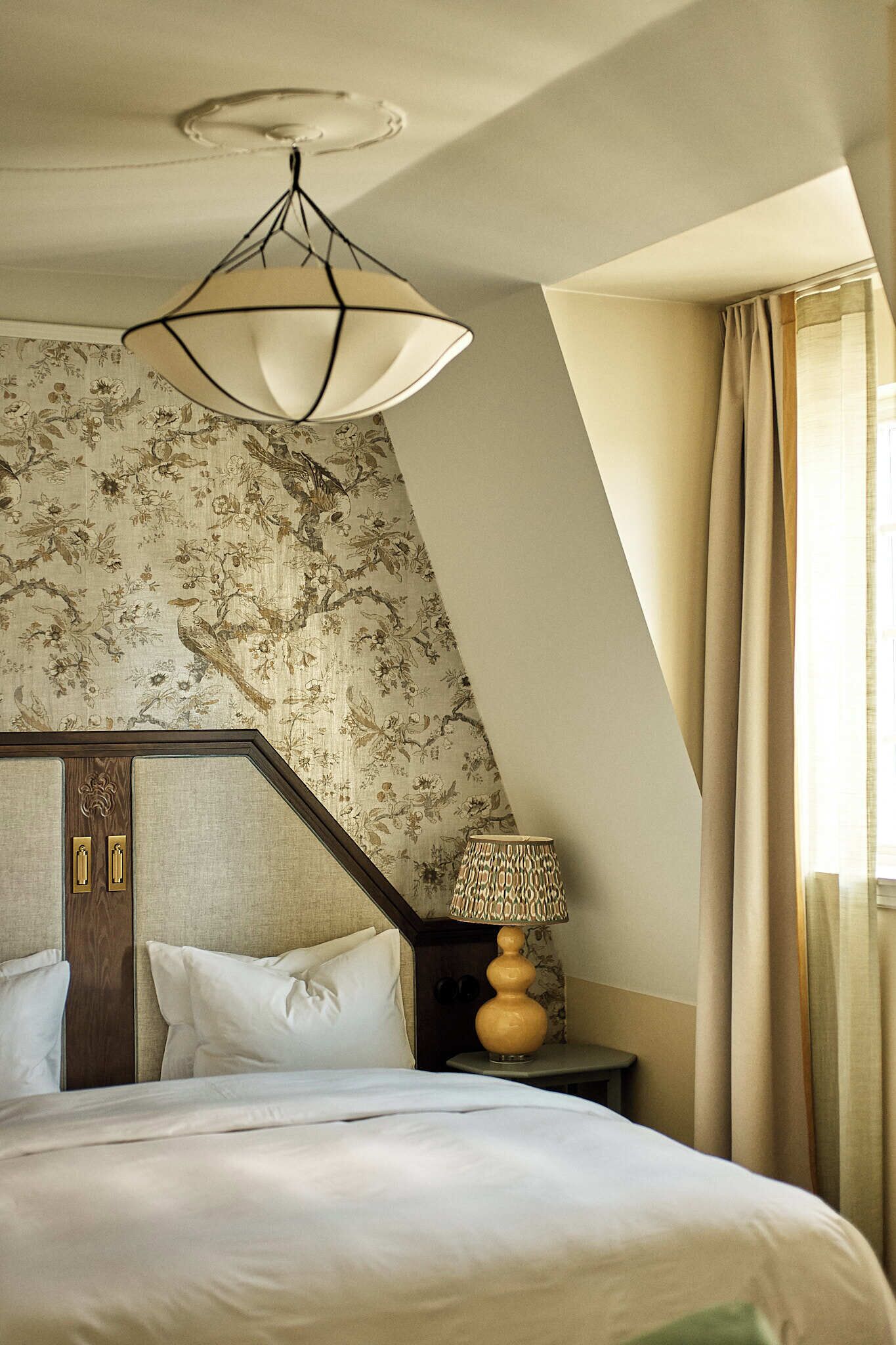 Une chambre à coucher comprenant un lit, une table de chevet, une lampe et un luminaire au plafond.