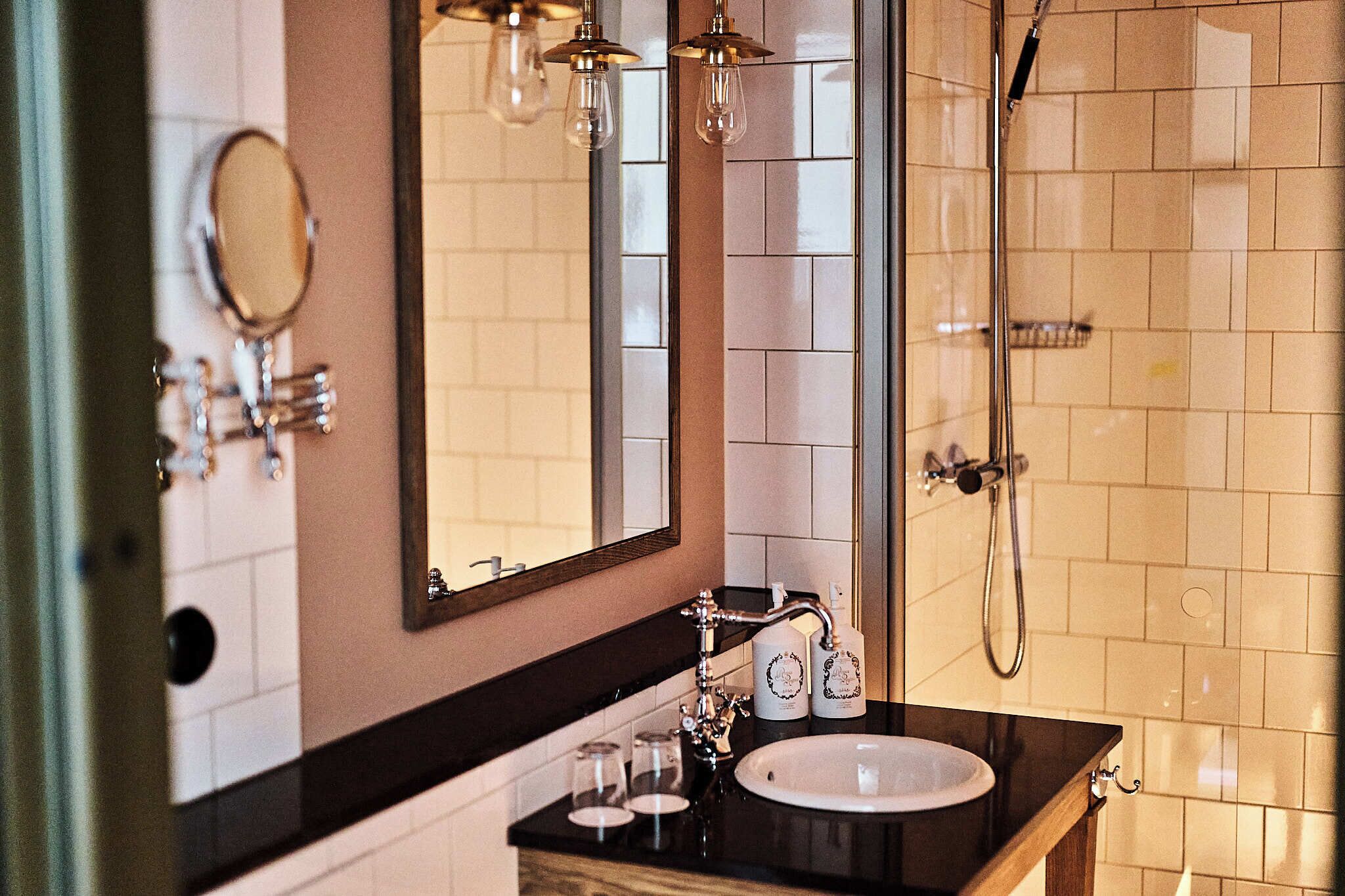 A bathroom with a sink, mirror, and shower.