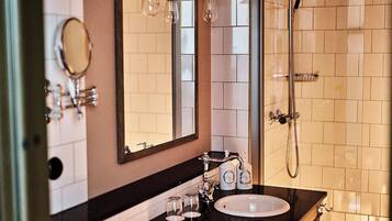 A bathroom with a sink, mirror, and shower.