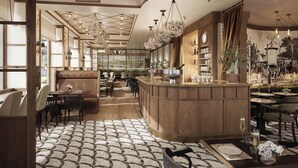 Un amplio vestíbulo de hotel con un bar central, zonas de estar y un suelo estampado.