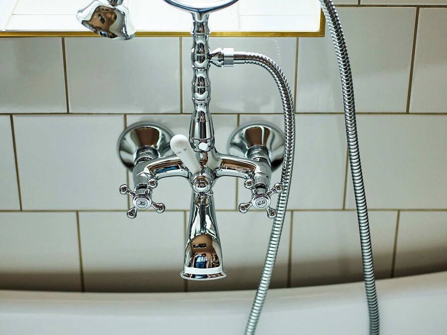 A chrome showerhead with a flexible hose, mounted on a tiled wall.