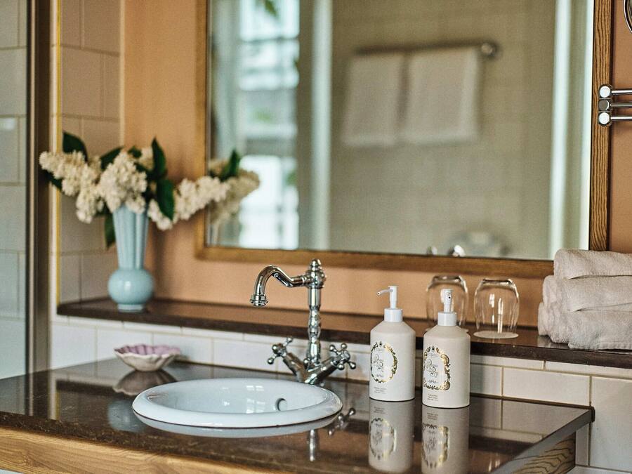 Un baño con lavamanos, espejo, toallero y artículos de aseo.