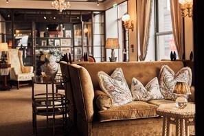 Une pièce chaleureuse avec un canapé marron, des coussins décoratifs, une petite table ronde avec une lampe et un fauteuil.