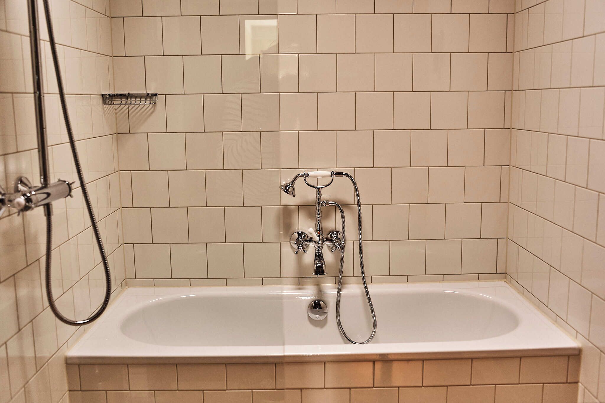 A bathroom with a bathtub, a shower head, and a handheld shower attachment.
