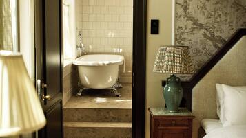 Una habitación con una bañera, una lámpara y una cama.
