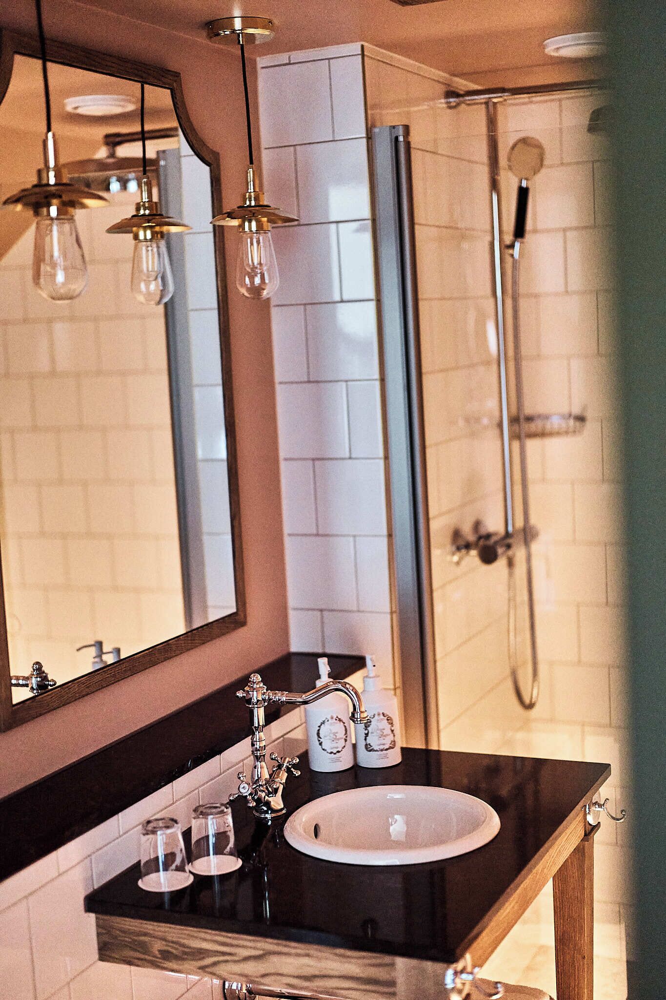 A modern bathroom with a large mirror, a sink, and a shower.