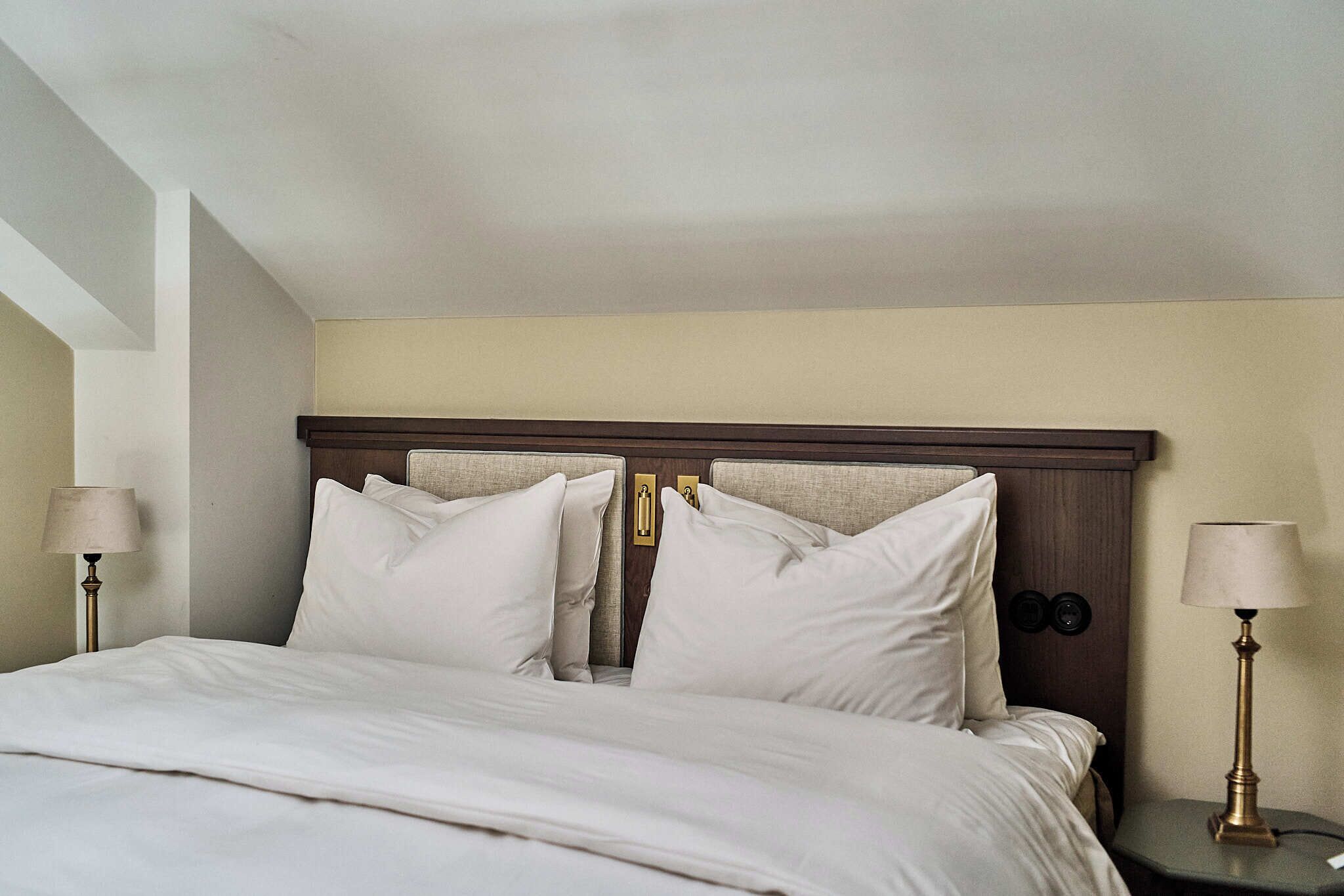 A hotel room with a large bed, two bedside lamps, and a wooden headboard.