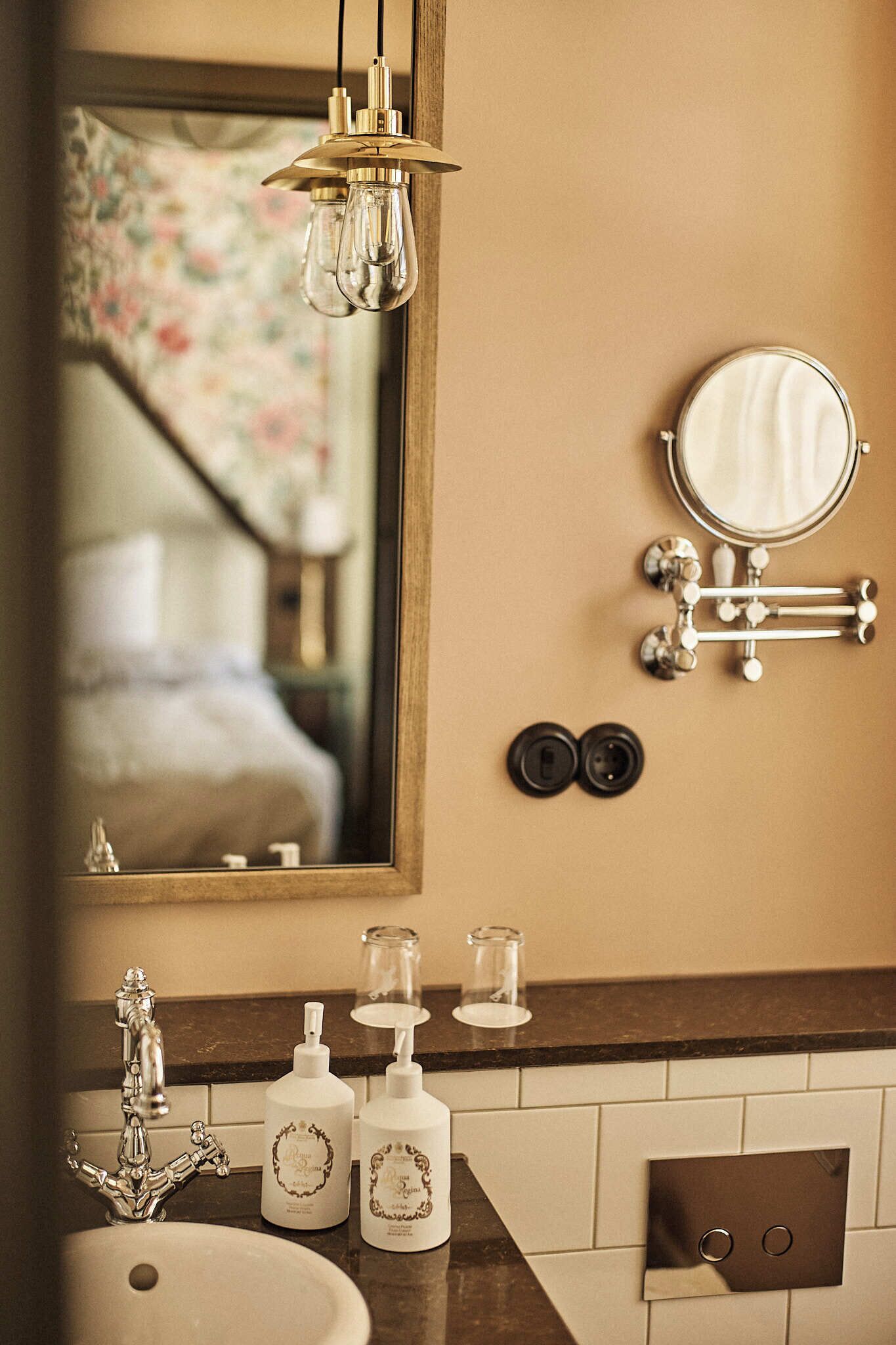 A bathroom with a mirror, a sink, a faucet, and two bottles of hand soap.