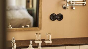 A bathroom with a mirror, a sink, a faucet, and two bottles of hand soap.