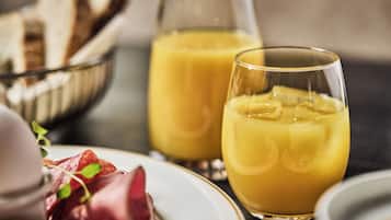 A breakfast setting with a glass of orange juice, a bowl of bread, and a bottle of juice.