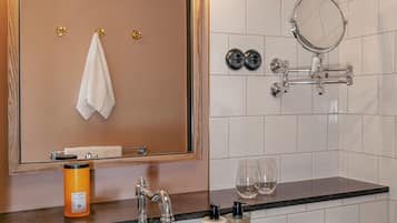 Ein Badezimmer mit großem Spiegel, Waschbecken, Handtuchhalter und Duschbereich.