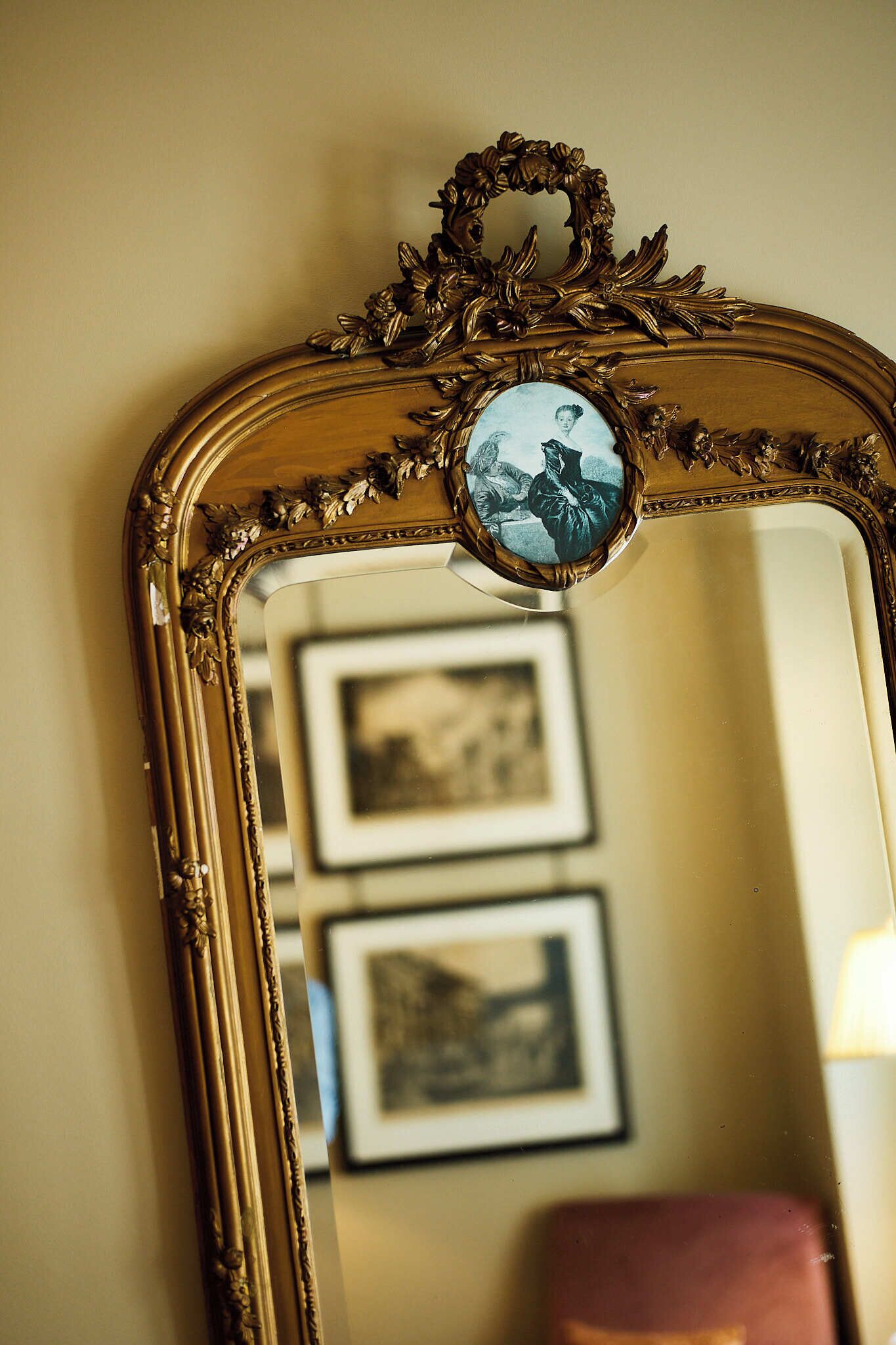 A mirror with an ornate gold frame and a round inset mirror.