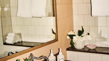 Un baño con encimera de mármol, un lavamanos blanco, un espejo y un perchero para toallas.