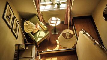 A room with a sofa, a small table, a lamp, and a window with curtains.