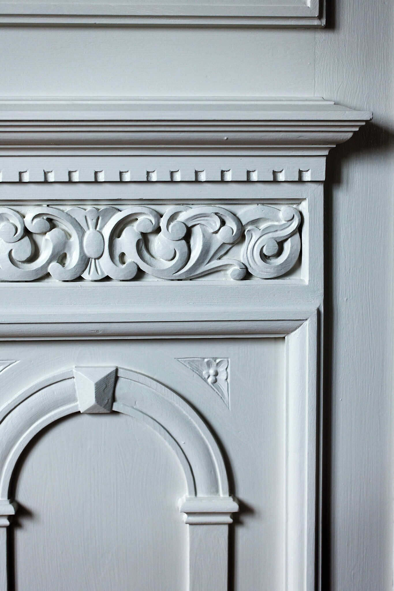 Primer plano de un detalle arquitectónico blanco con elaboradas esculturas y un arco decorativo.