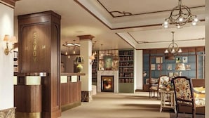 Un vestíbulo con recepción, estanterías, chimenea y candelabro.