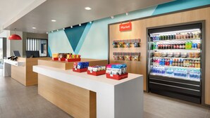 A modern reception area with a counter, a refrigerator stocked with beverages, and a wall with a 'Market' sign. - avid Hotel Ocala Downtown by IHG (Ocala)