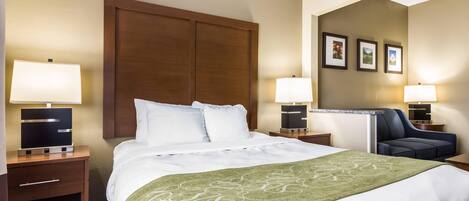 A hotel room with a large bed, two bedside tables with lamps, a chair, and a mirror.