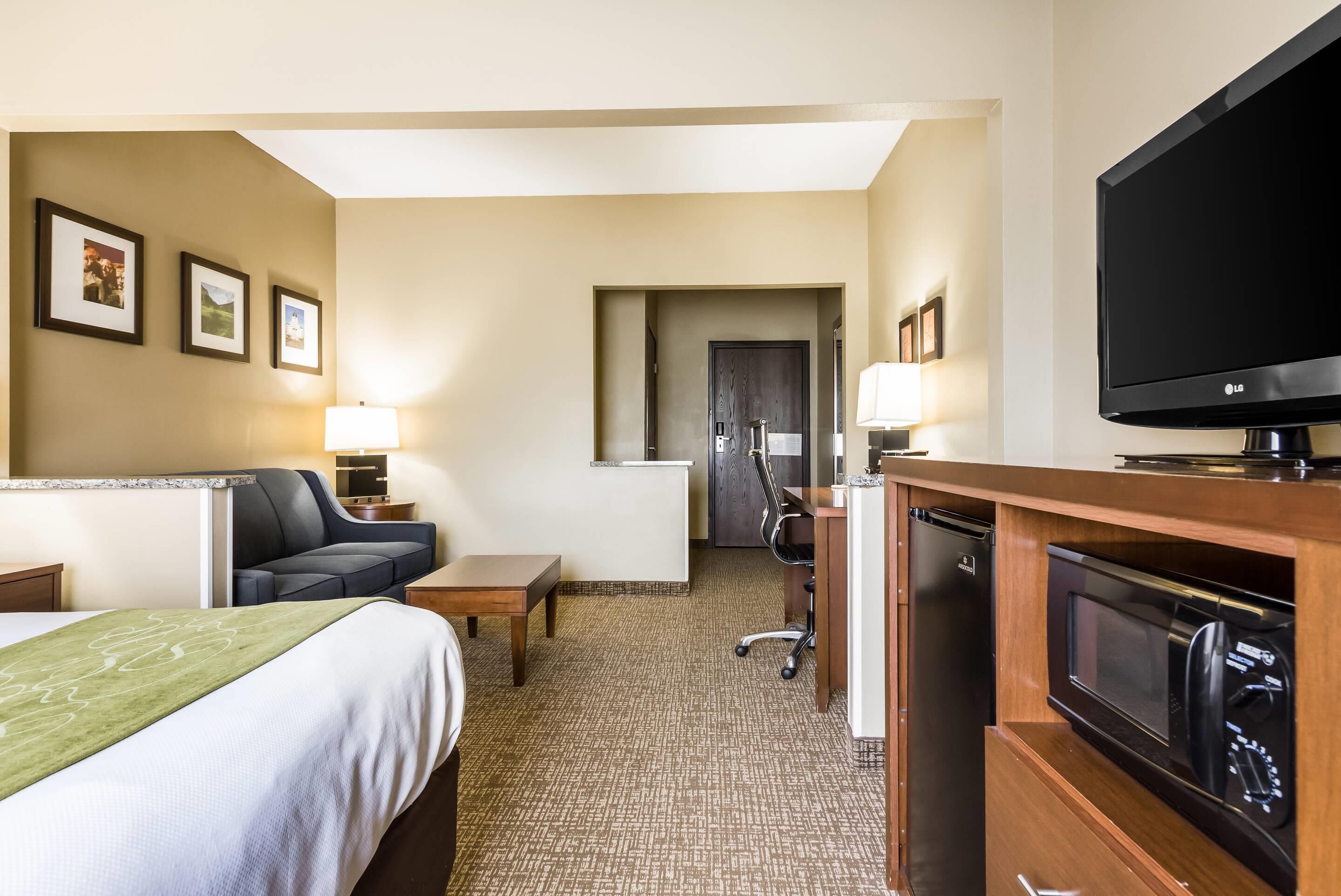 Habitación de hotel con cama, escritorio, silla, televisor, microondas y refrigerador.