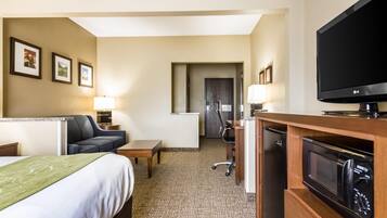 Habitación de hotel con cama, escritorio, silla, televisor, microondas y refrigerador.