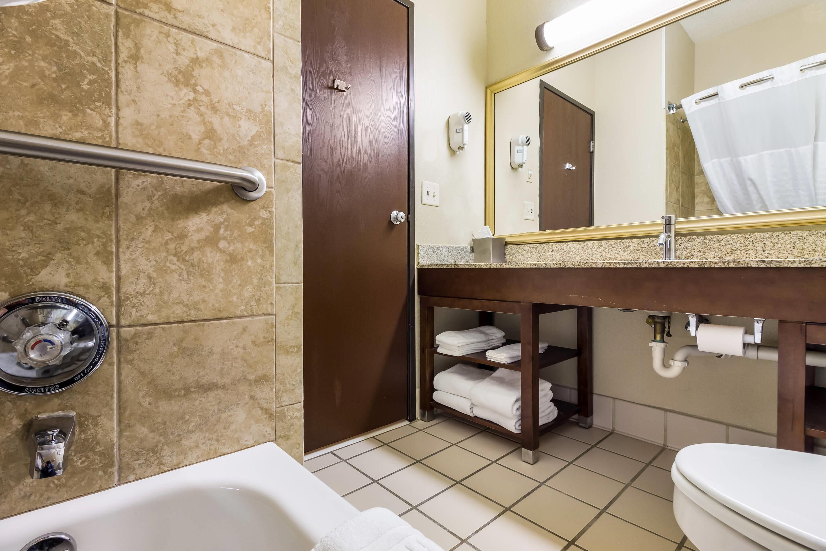 A bathroom with a bathtub, a toilet, a sink with a mirror, a towel rack, and a shower curtain.